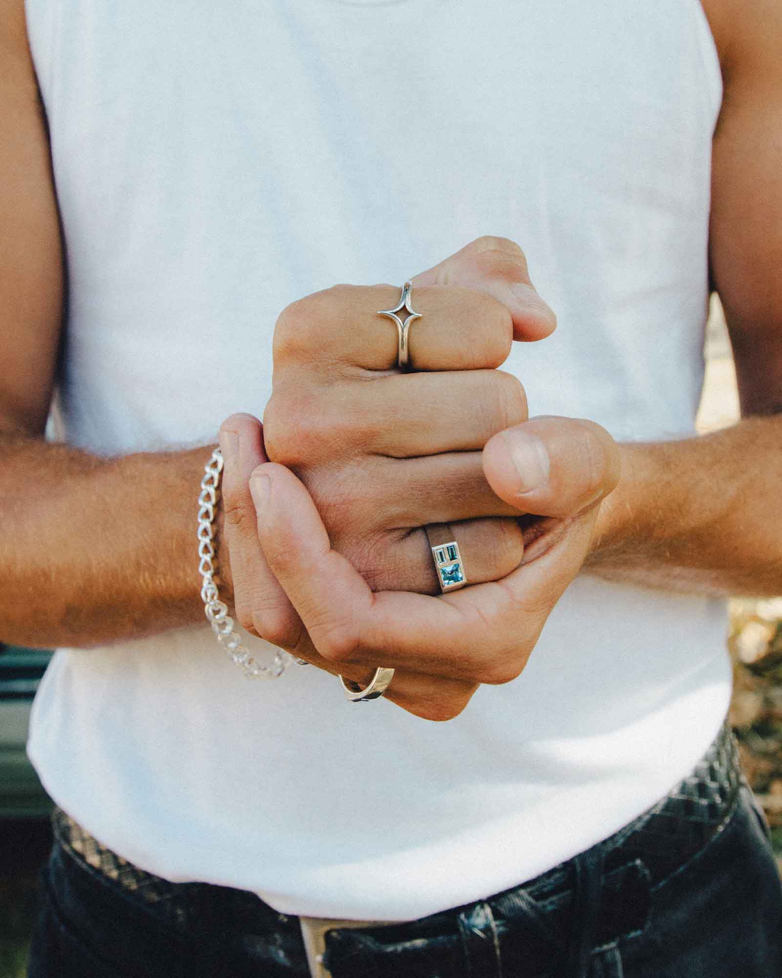 Close up of a person playing rock, papers and scissors while facing the camera and wearing rings.
