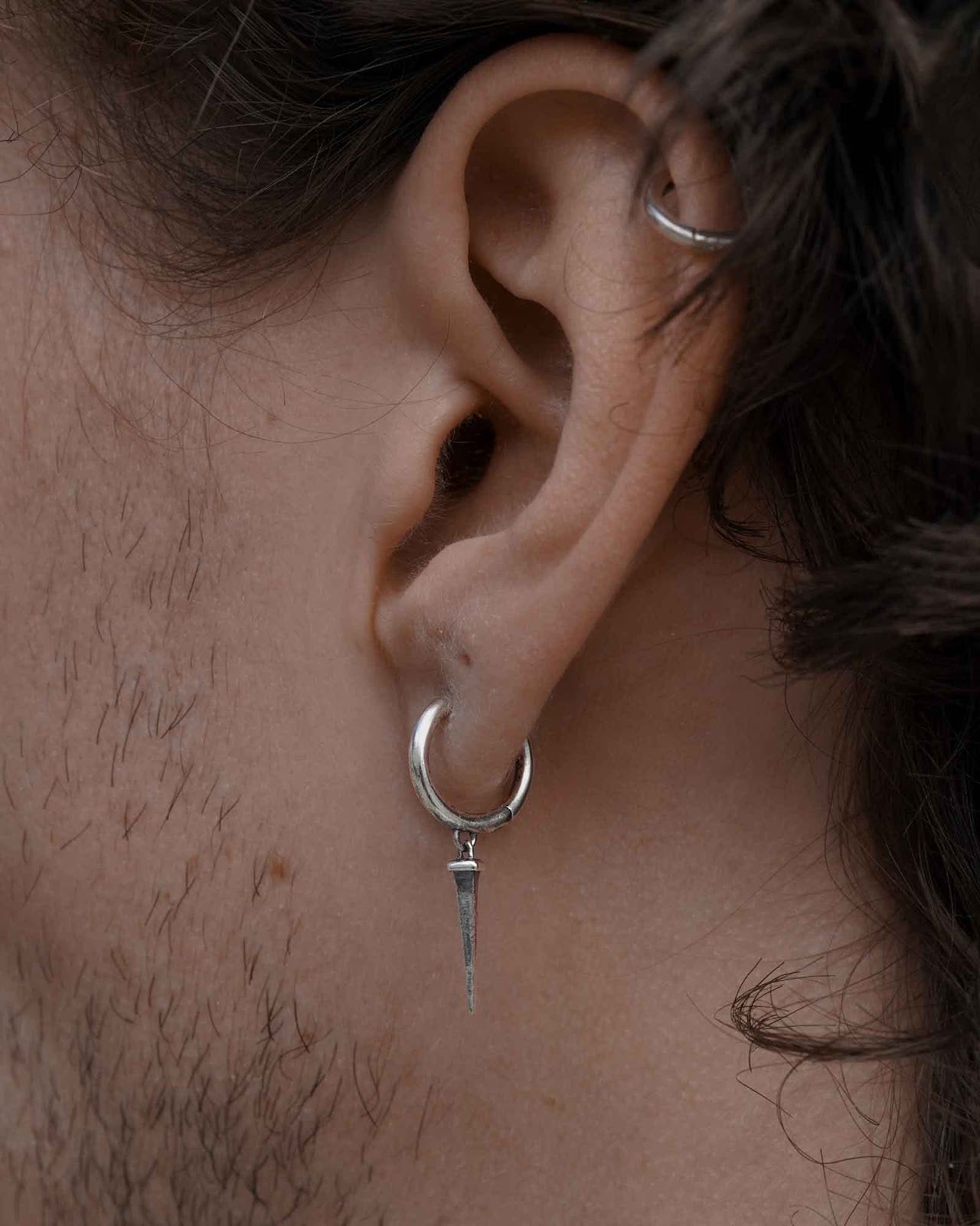 Nail huggie earring worn on the ear