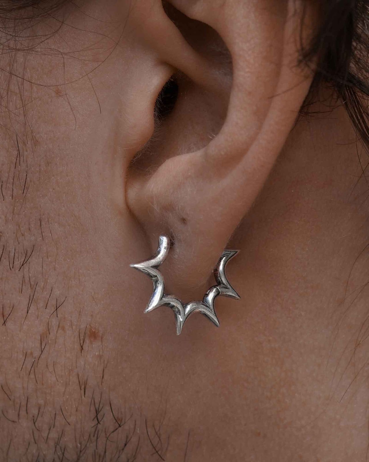Black and white portrait of a person wearing a burst huggie earring