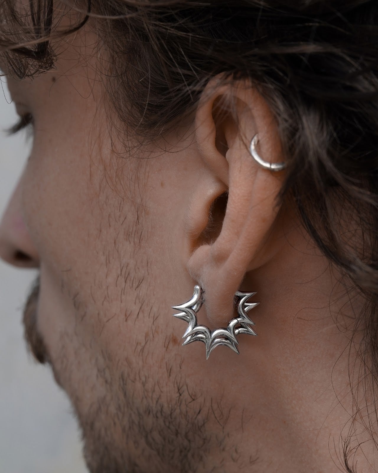 Close-up of an ear and neck wearing a burst huggie earring