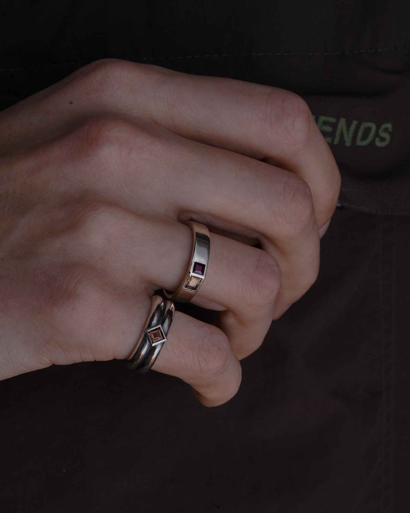 Close-up of a hand wearing two rings on a dark background