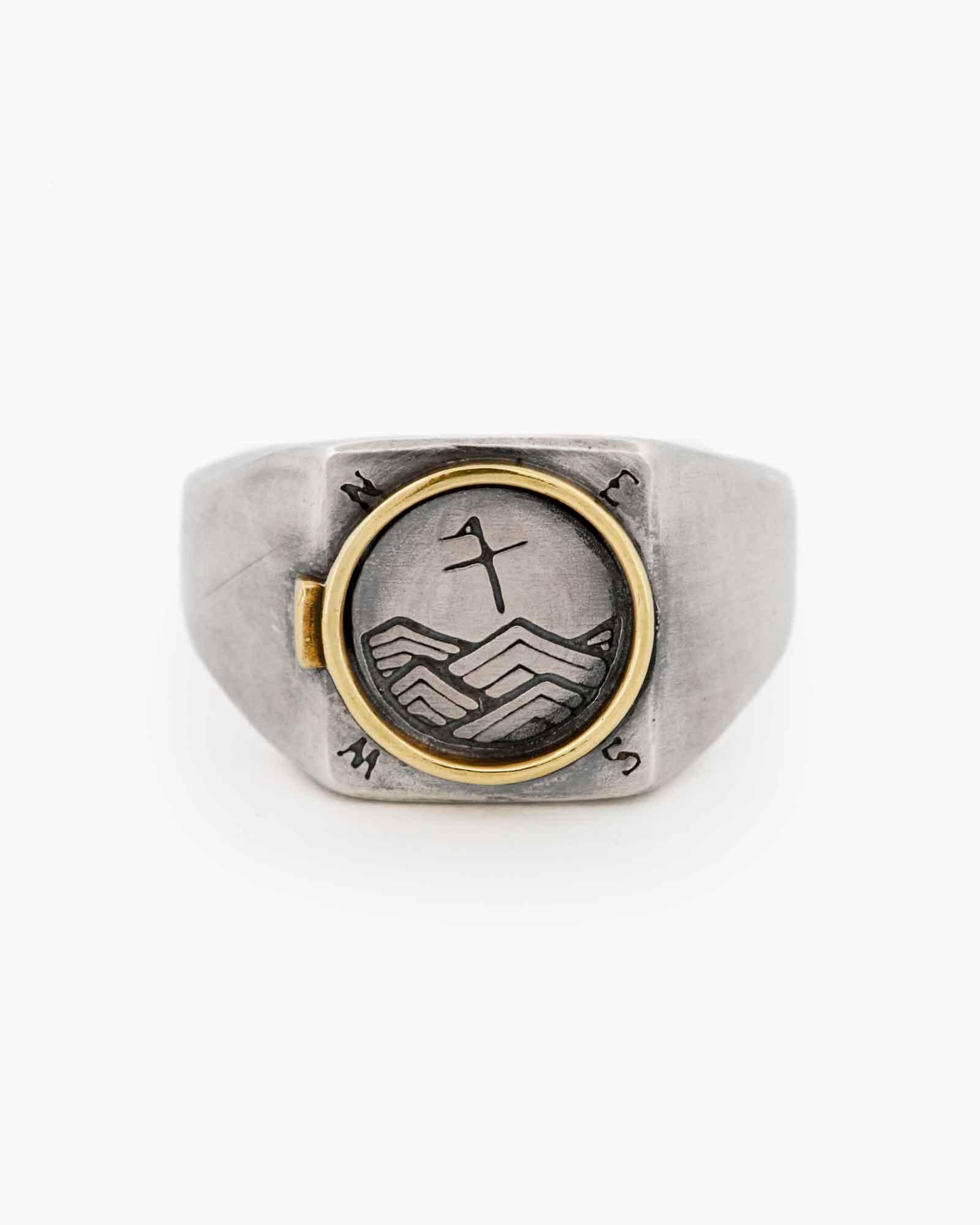 Silver ring with brass accents and engraved design on a white background