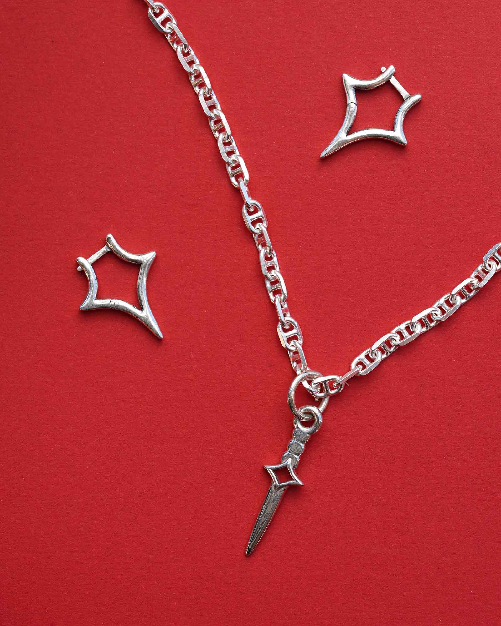 Silver necklace with a dagger blade pendant on a red background