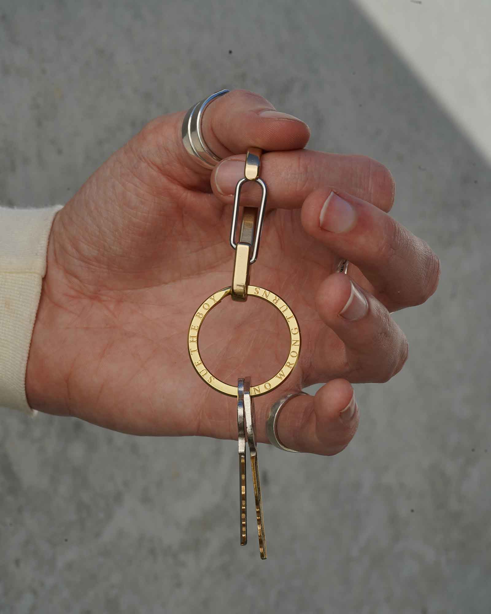 Hand holding a gold keychain with a concrete background