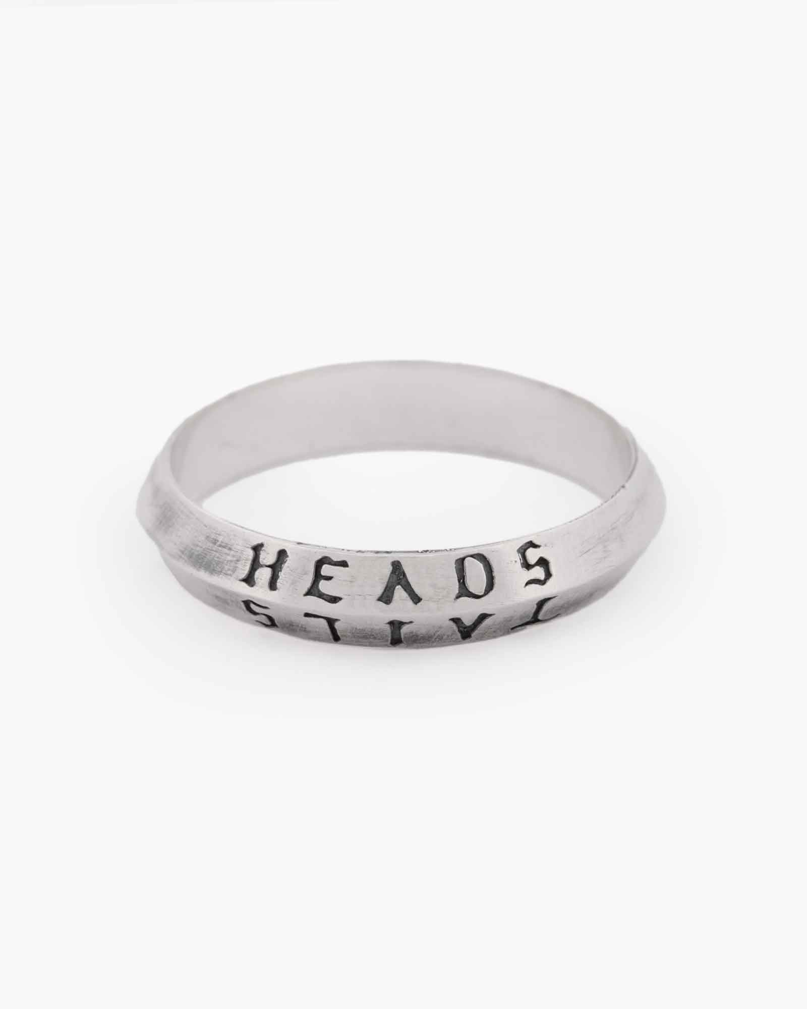 Silver ring with 'HEADS' and 'TAILS' text on a white background