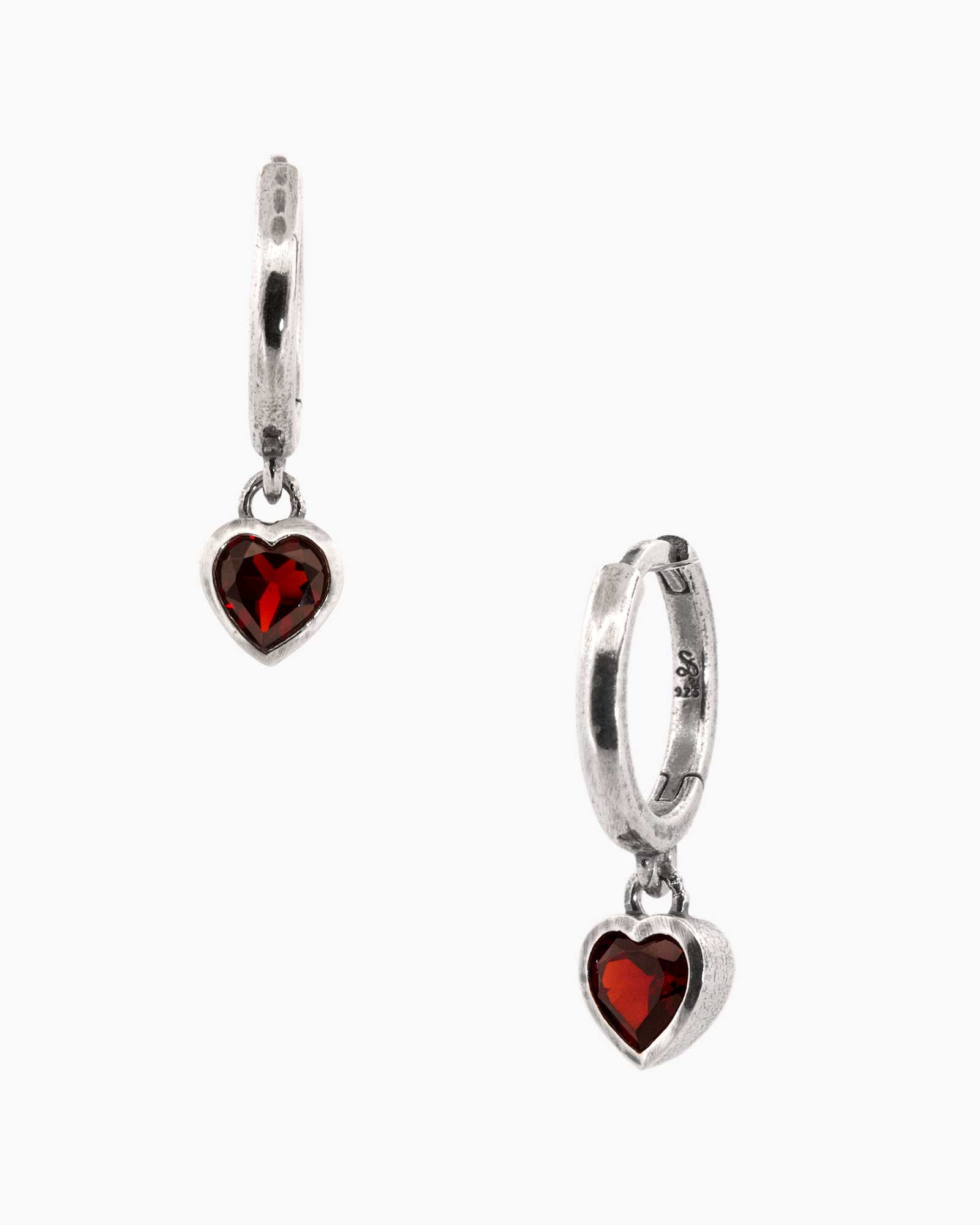 Silver hoop earrings with heart-shaped red gemstones on a white background