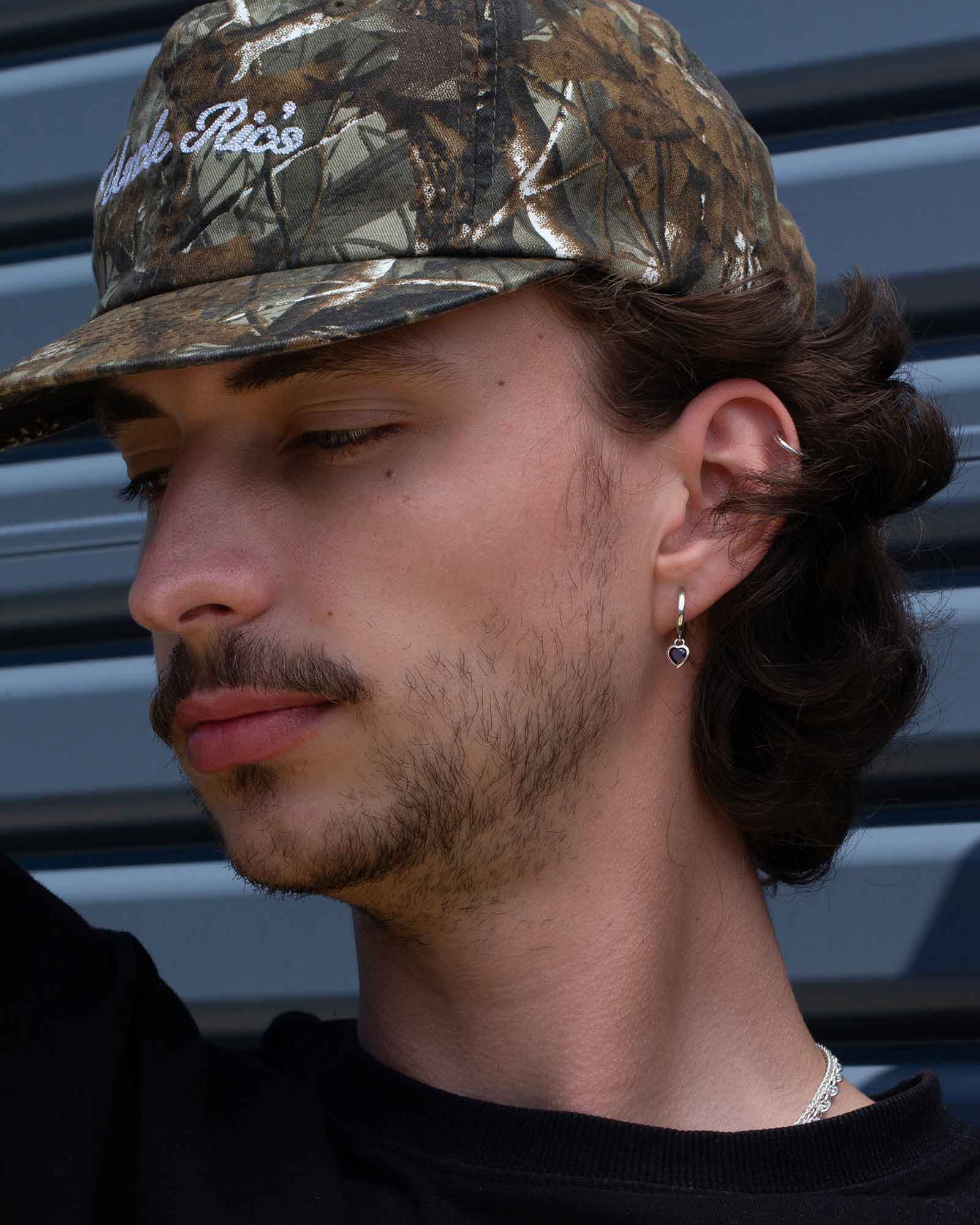 Man wearing silver earrings, looking to the side.