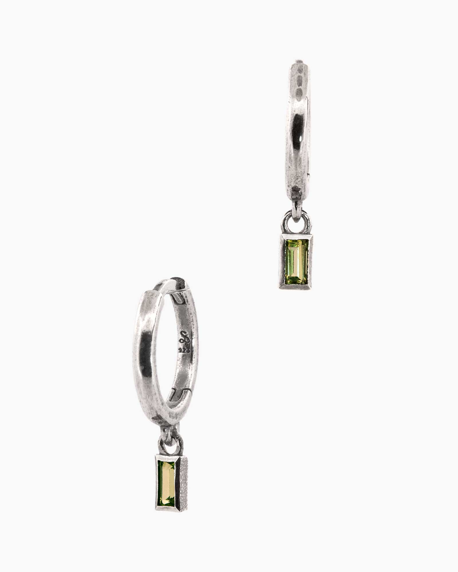 Pair of silver hoop earrings with green gemstones on a white background
