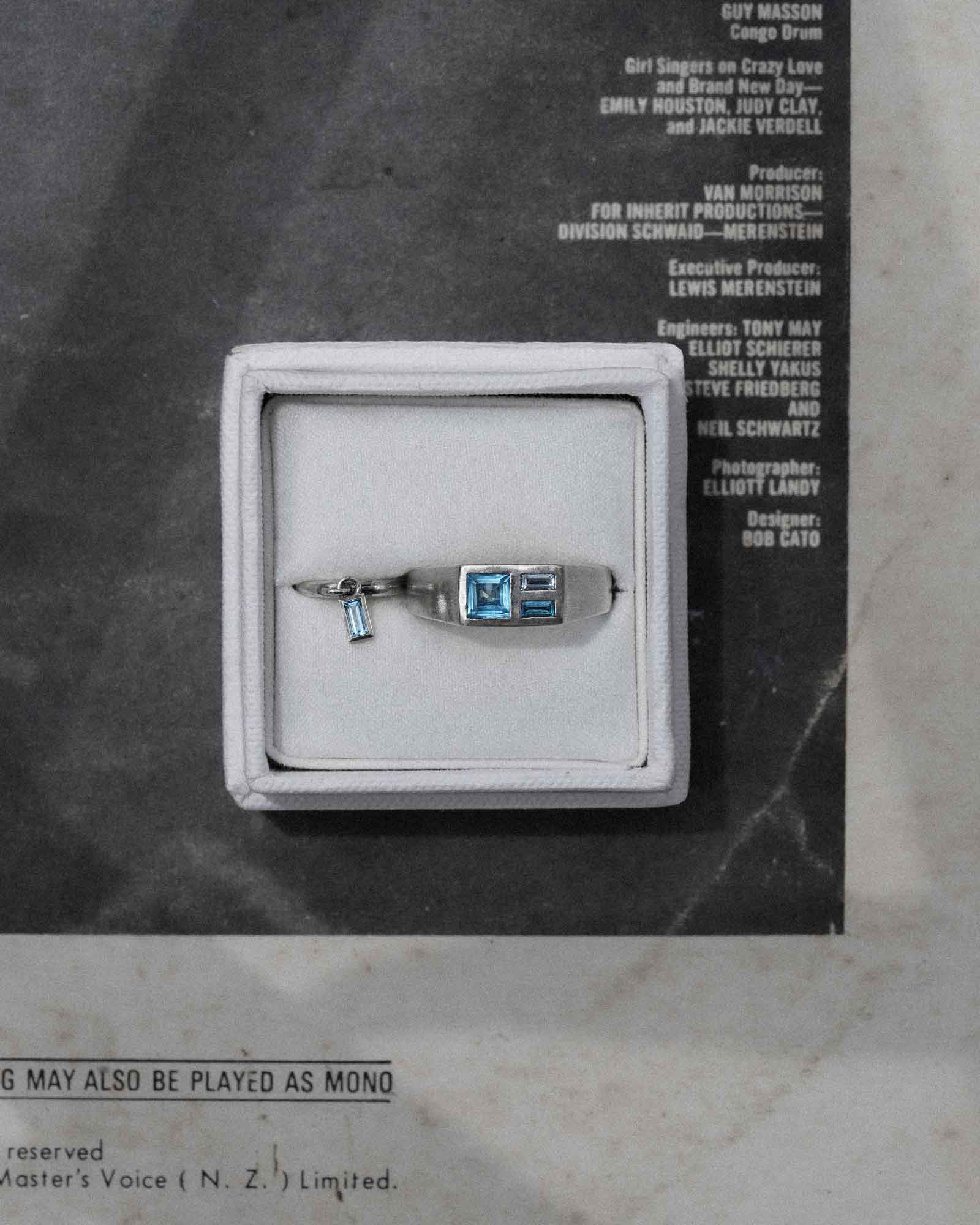Silver ring and earring with blue gemstone in a box on a vintage record sleeve background