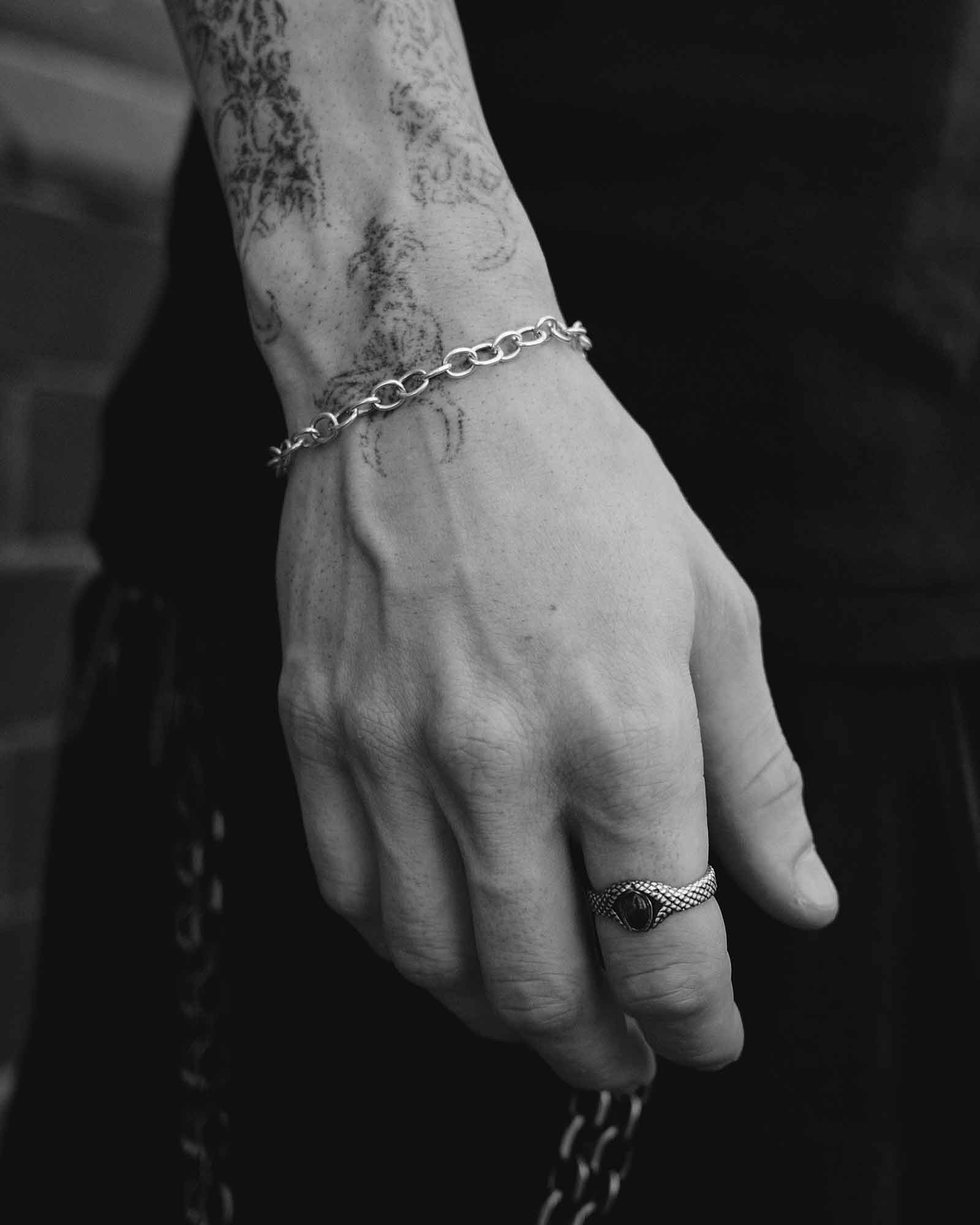 Close-up of a hand with a bracelet and ring, with a dark background