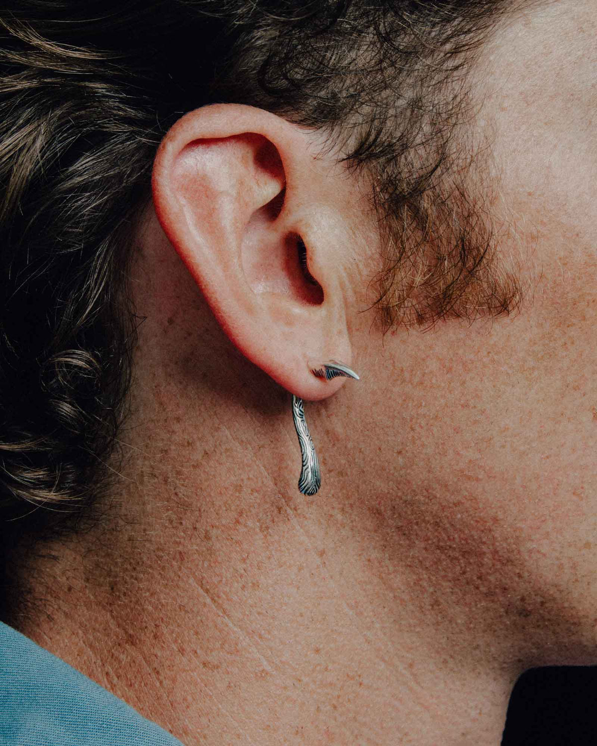 Close-up of a Sickle earring worn on the ear