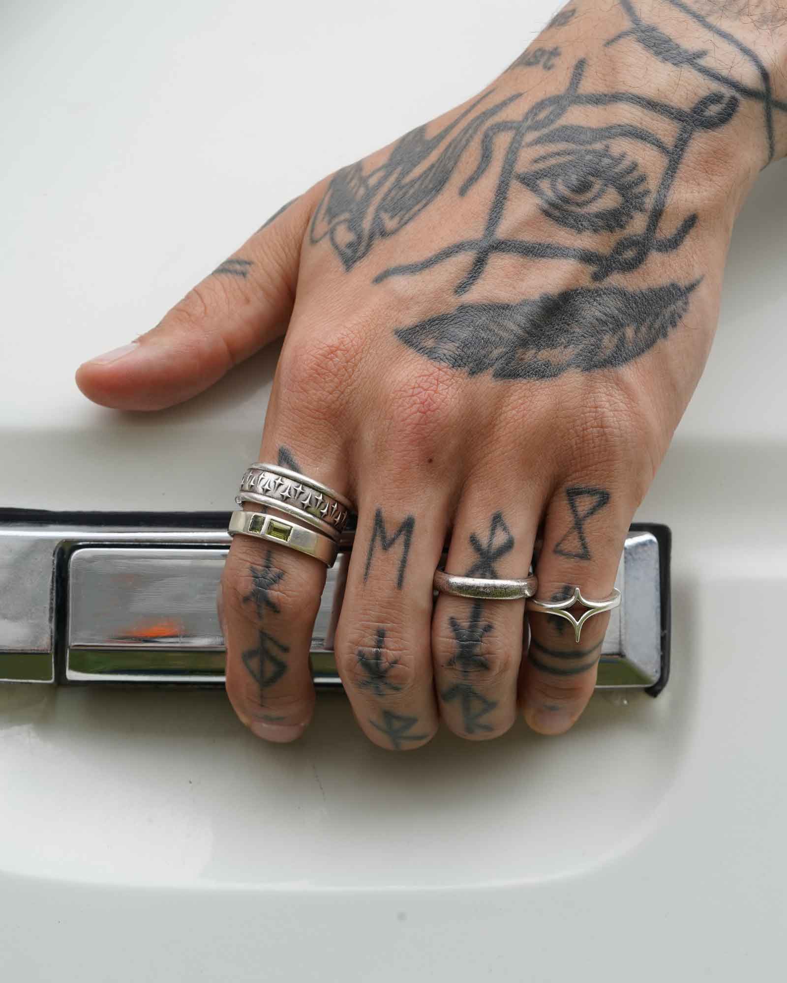 Hand with tattoos and rings on a car door handle