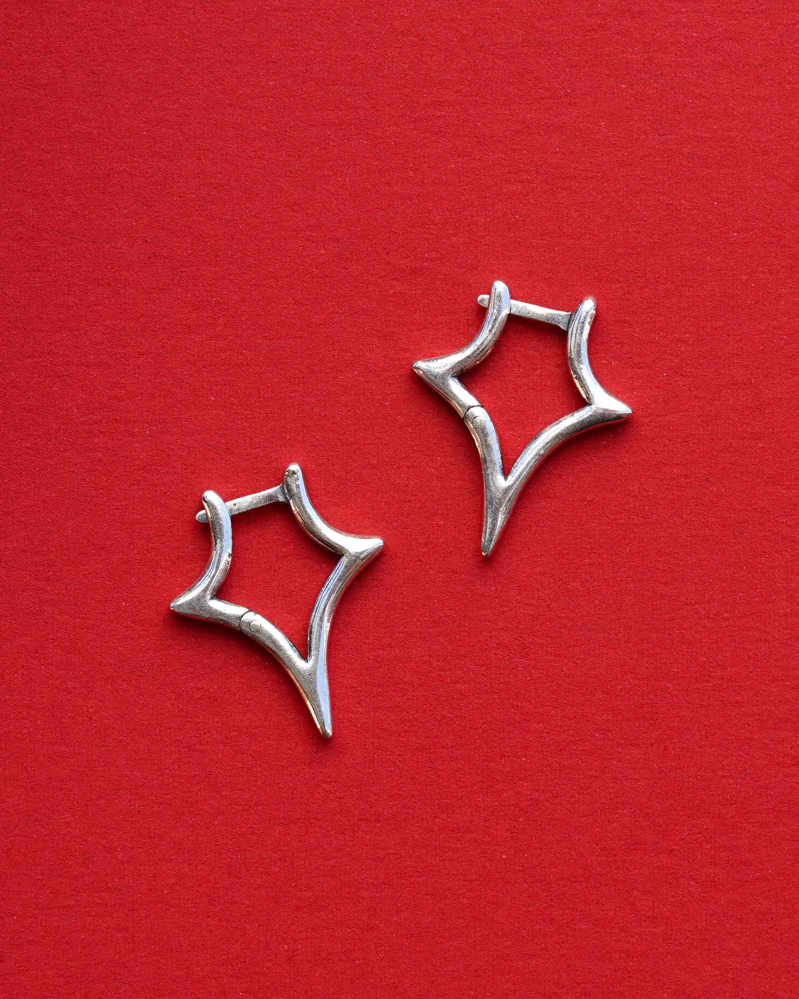 Silver star-shaped earrings on a red background