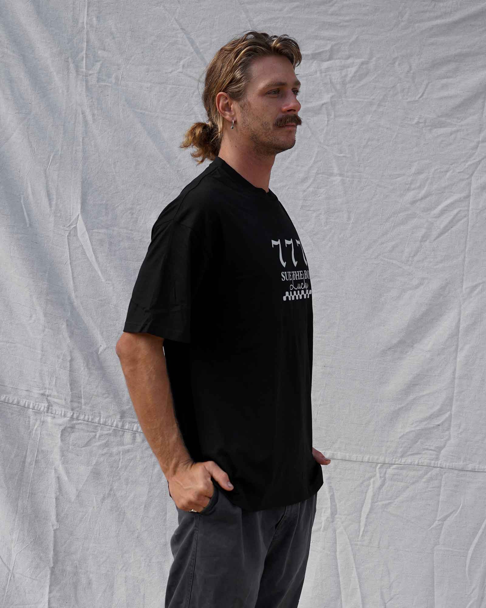 Man wearing a black t-shirt with text and graphics against a textured white background
