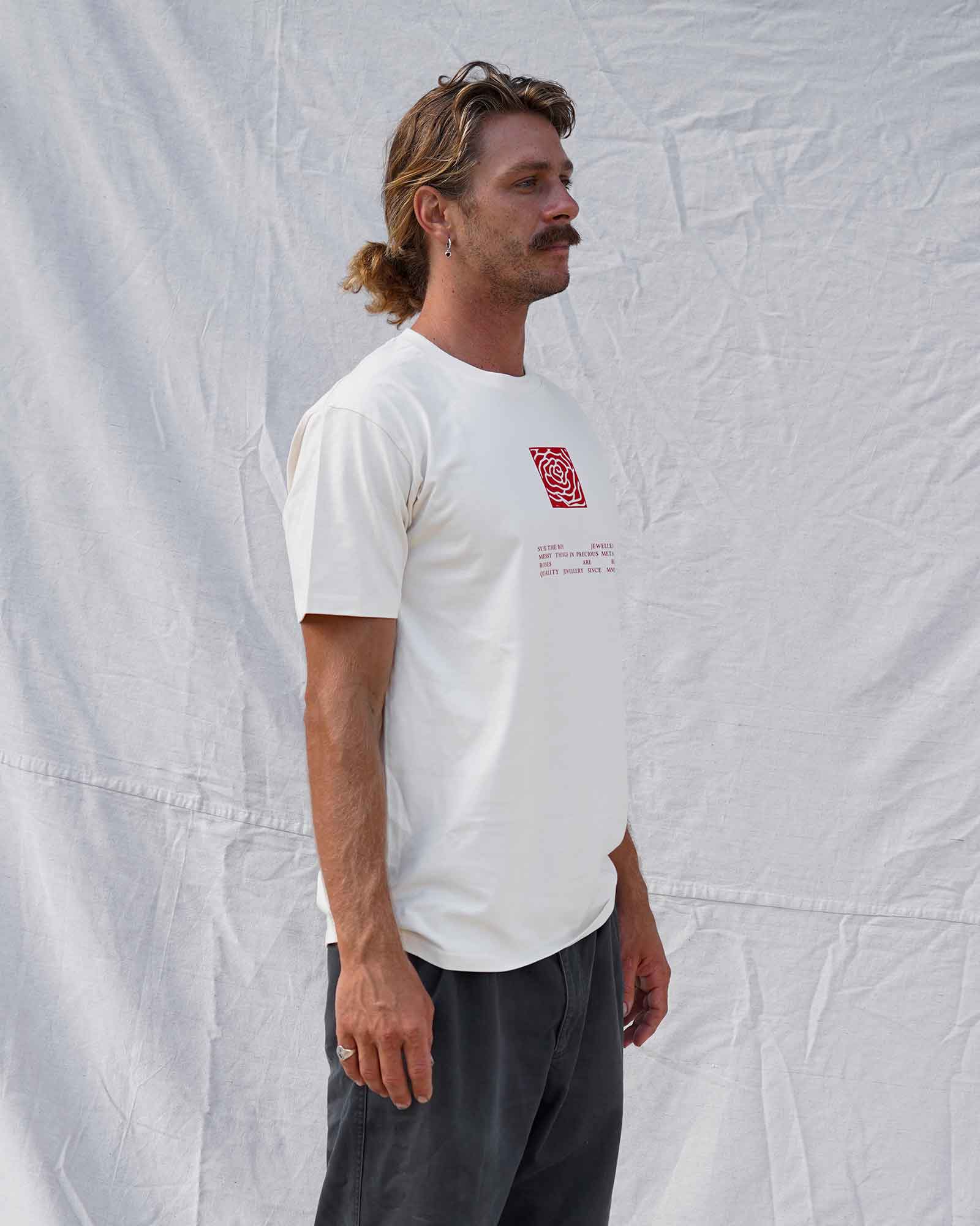 Man wearing a beige t-shirt with a red logo against a textured white background