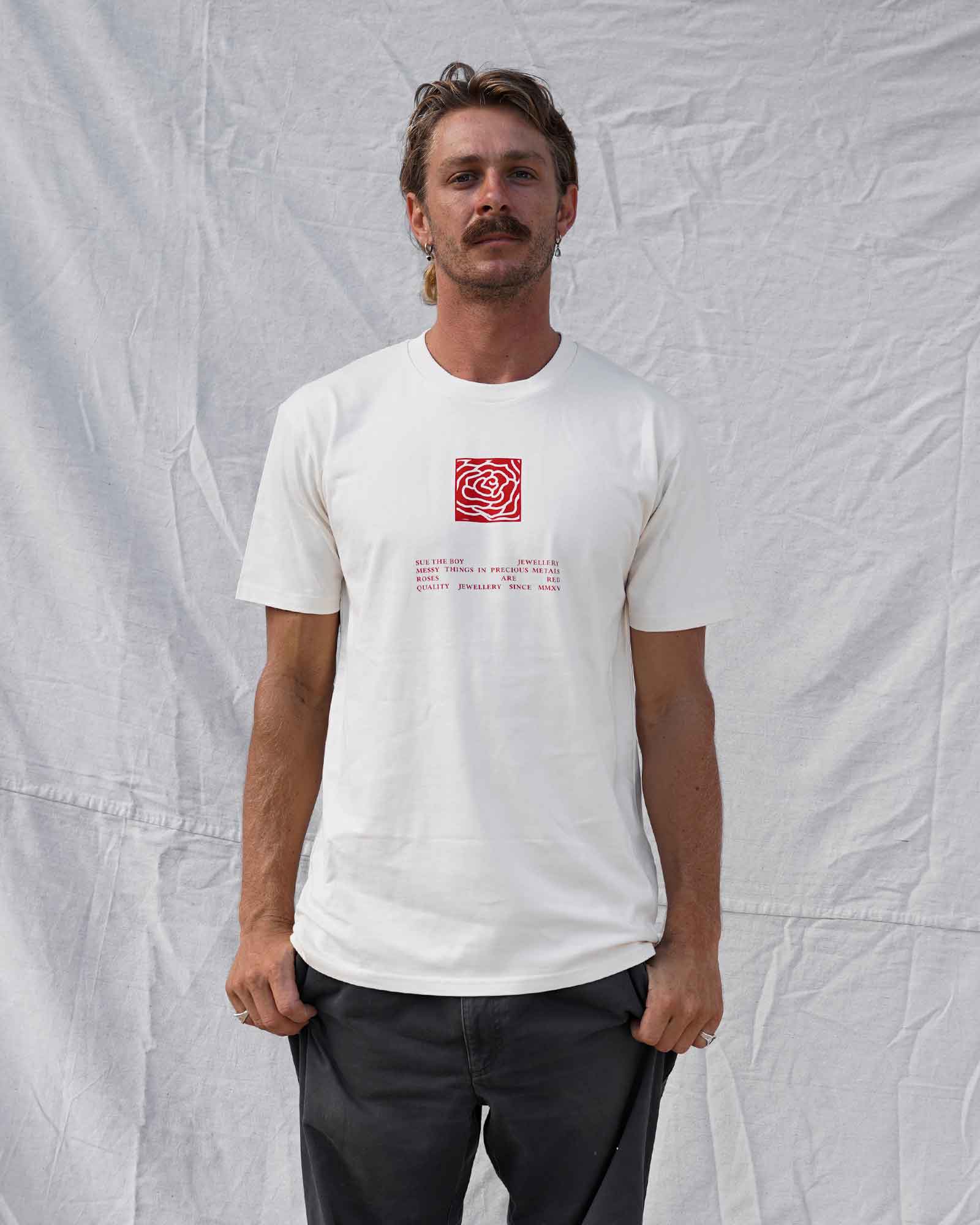 Man wearing a beige t-shirt with a red logo and text against a textured white background