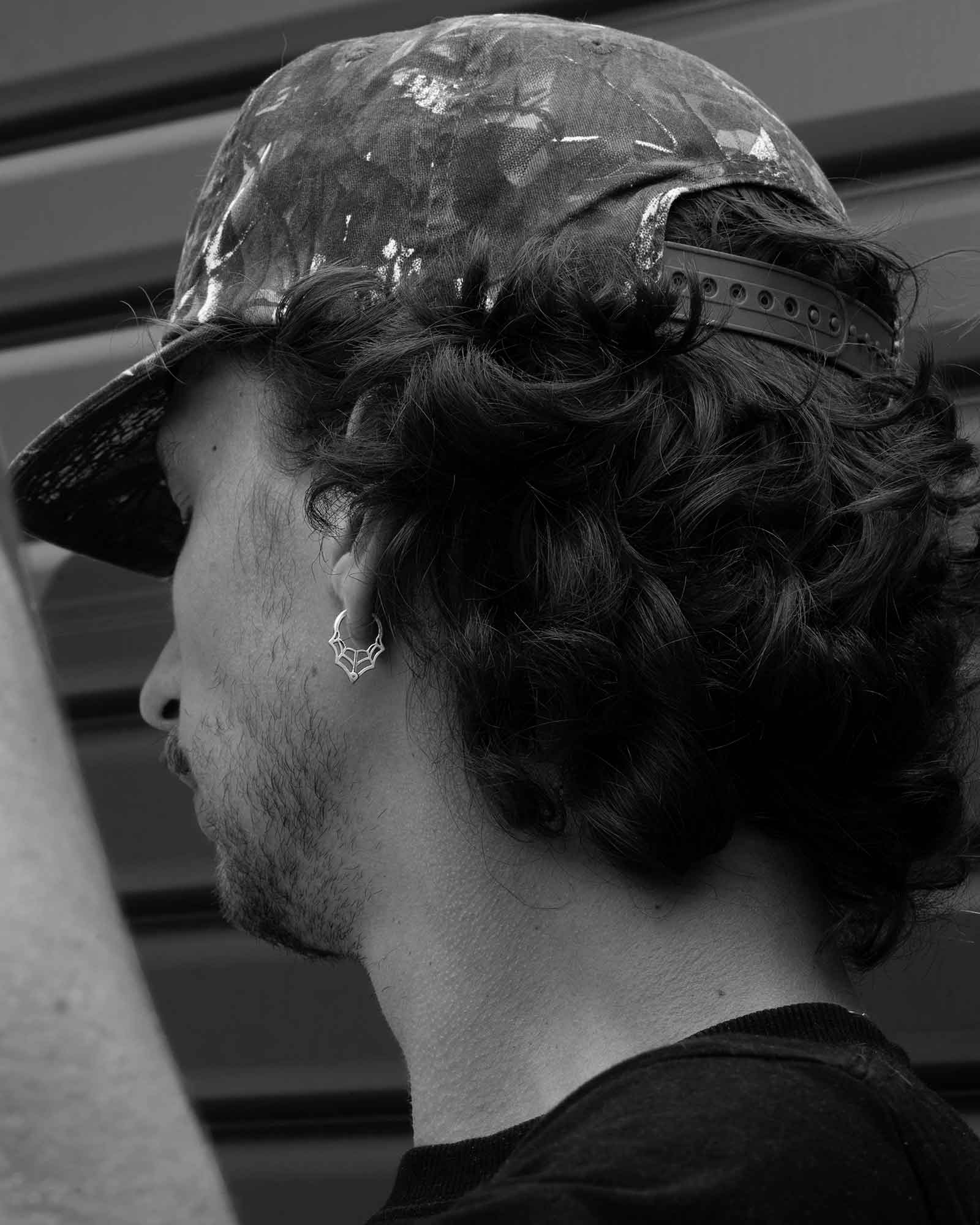 Person wearing a spider web huggie earring in black and white