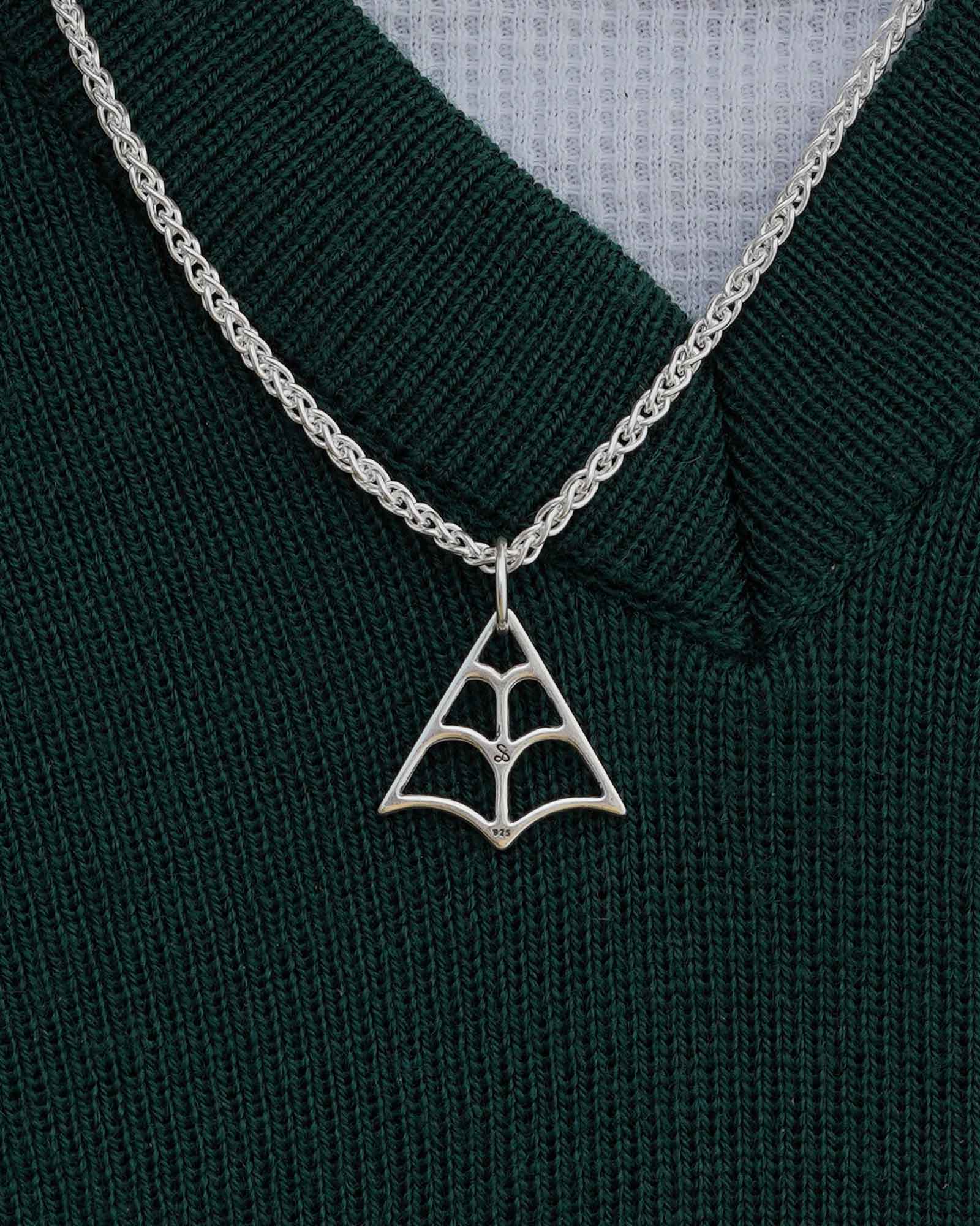 Silver spider web pendant necklace on a green sweater