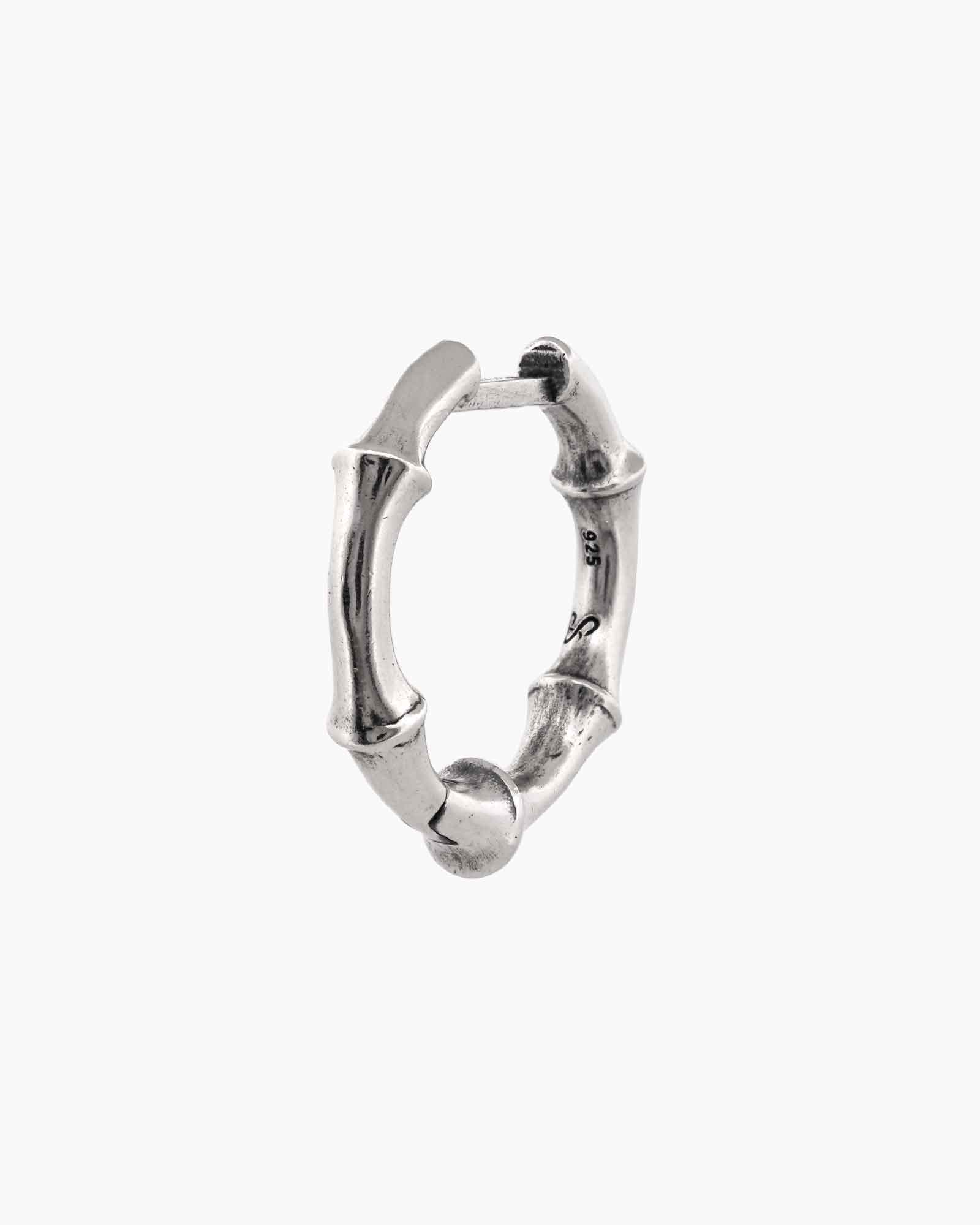 Pair of silver bone-shaped huggie earrings on a white background