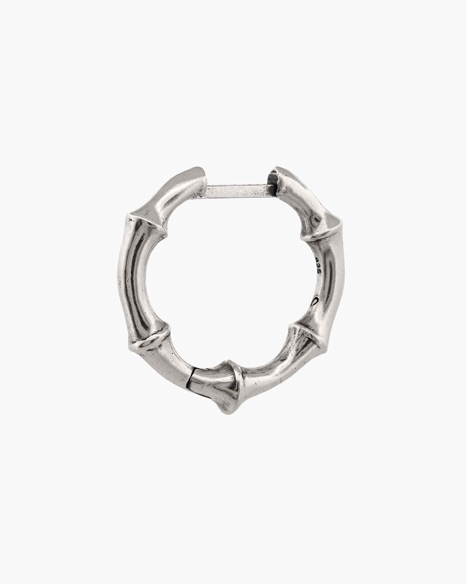 Silver bone-shaped huggie earring on a white background